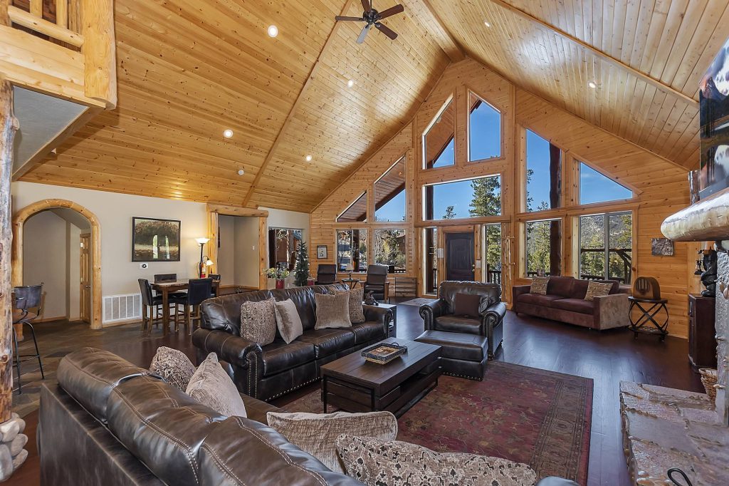 Golden Oak Estate living room with vaulted pine ceilings, stone fireplace, and rustic décor