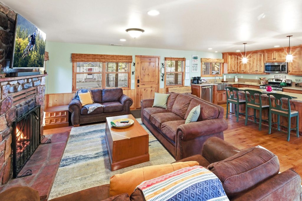 Cozy cabin living room interior at Crest Nest in Boulder Bay with fireplace, sofas, kitchen, and wooden finishes.