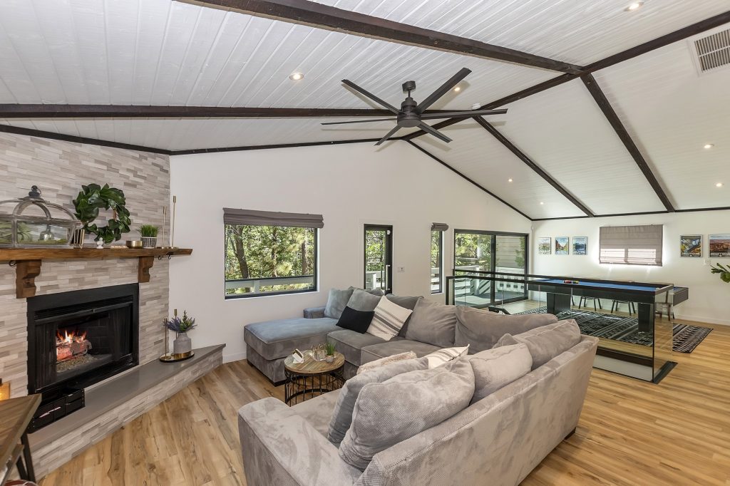 Spacious Knickerbocker Nest living room with fireplace, modern sofa seating, wood flooring, and game table area.