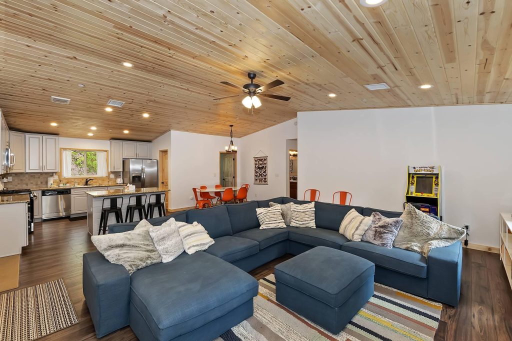 Spacious Evergreen Gables living room with large sectional sofa, modern kitchen, wood ceiling, and cozy cabin interior