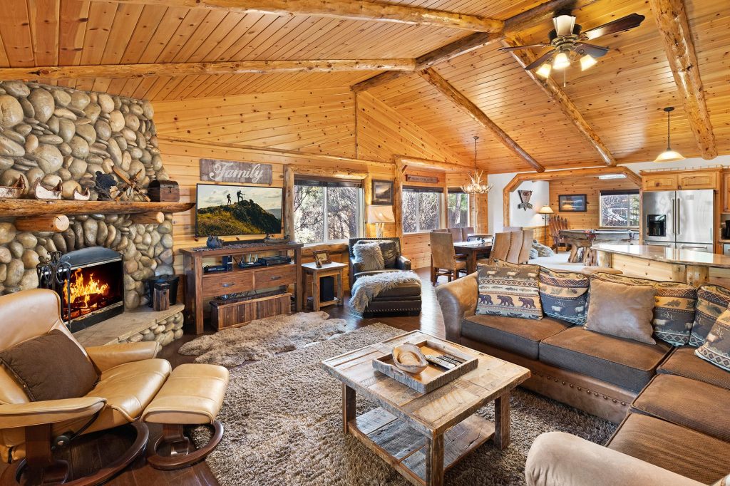 Eagle Mountain Lodge living room with stone fireplace, rustic wood interior, comfortable seating, dining area, and kitchen