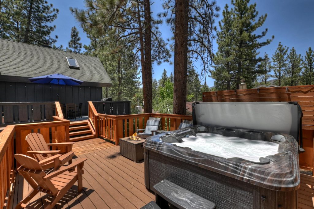 Kenny Cottage outdoor hot tub on a spacious wooden deck surrounded by pine trees and comfortable seating