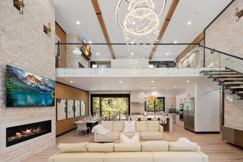 Modern living room in Castlewood Pines cabin, Big Bear, featuring a staircase and a cozy fireplace.