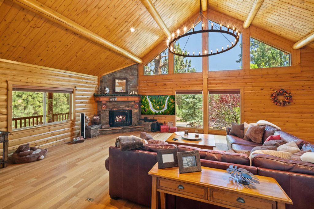 A spacious living room in Alderwood Haven cabin in Big Bear, featuring a cozy fireplace and elegant wood paneling.