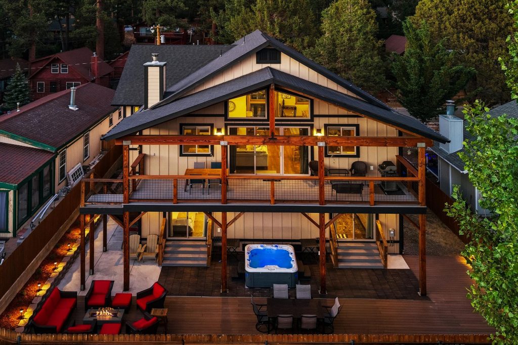 Exterior view of Five Little Bears cabin with spacious decks, outdoor seating, hot tub, and mountain surroundings in Big Bear Lake, CA