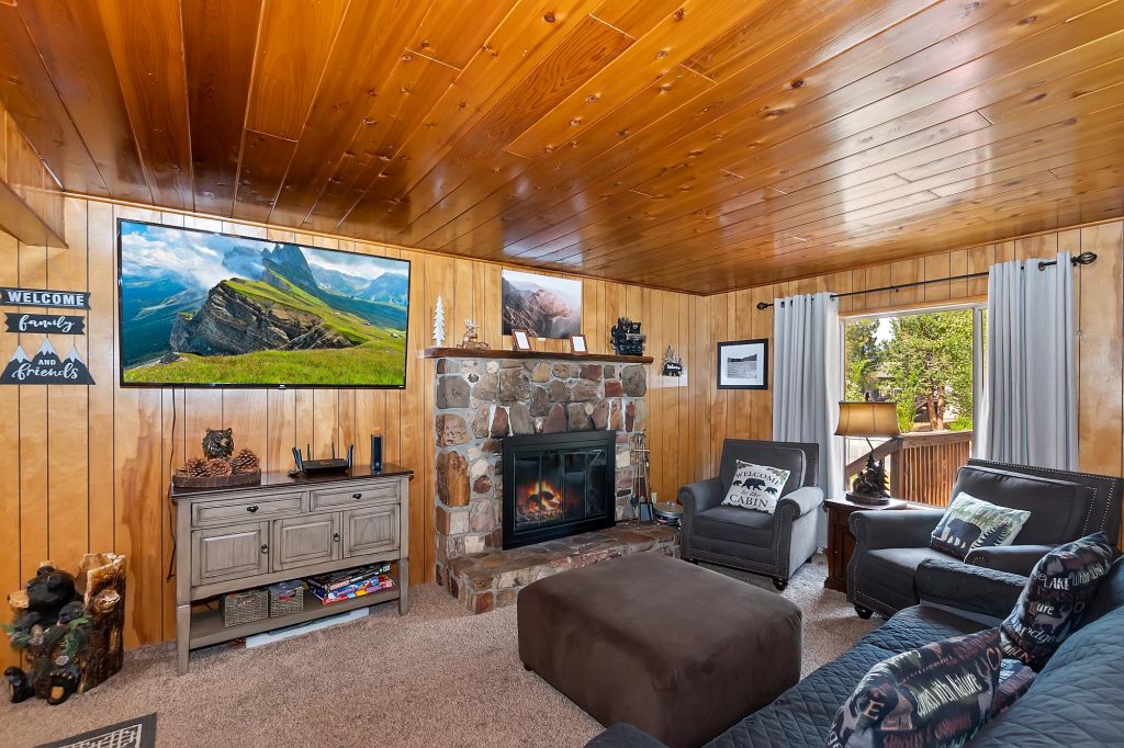 Family and Friends Retreat cabin living room with stone fireplace, wooden walls, cozy seating, and rustic mountain decor.