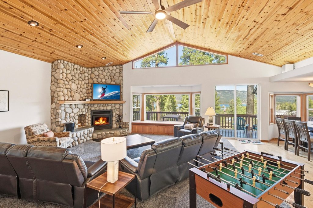 Tree Top Haven cabin living room with stone fireplace, leather seating, foosball table, and scenic Big Bear Lake views.