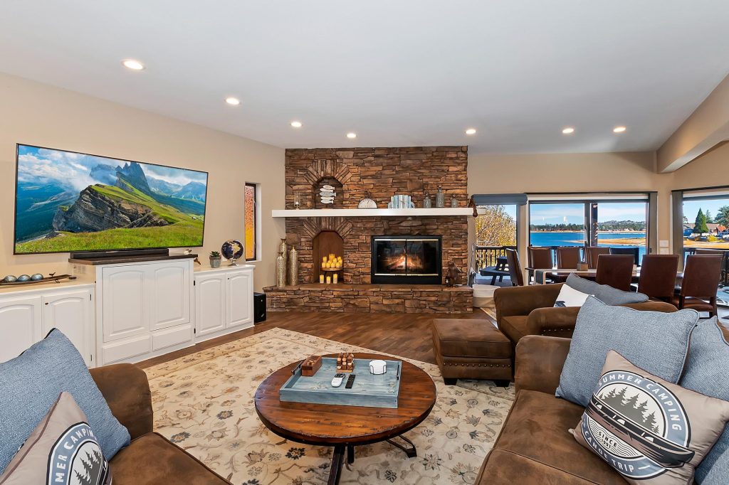 Modern luxury cabin living room with stone fireplace, comfortable seating, and lake views