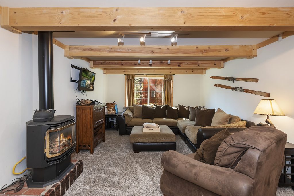 The Great Escape cabin interior with wood beams, fireplace stove, cozy seating, and rustic mountain decor