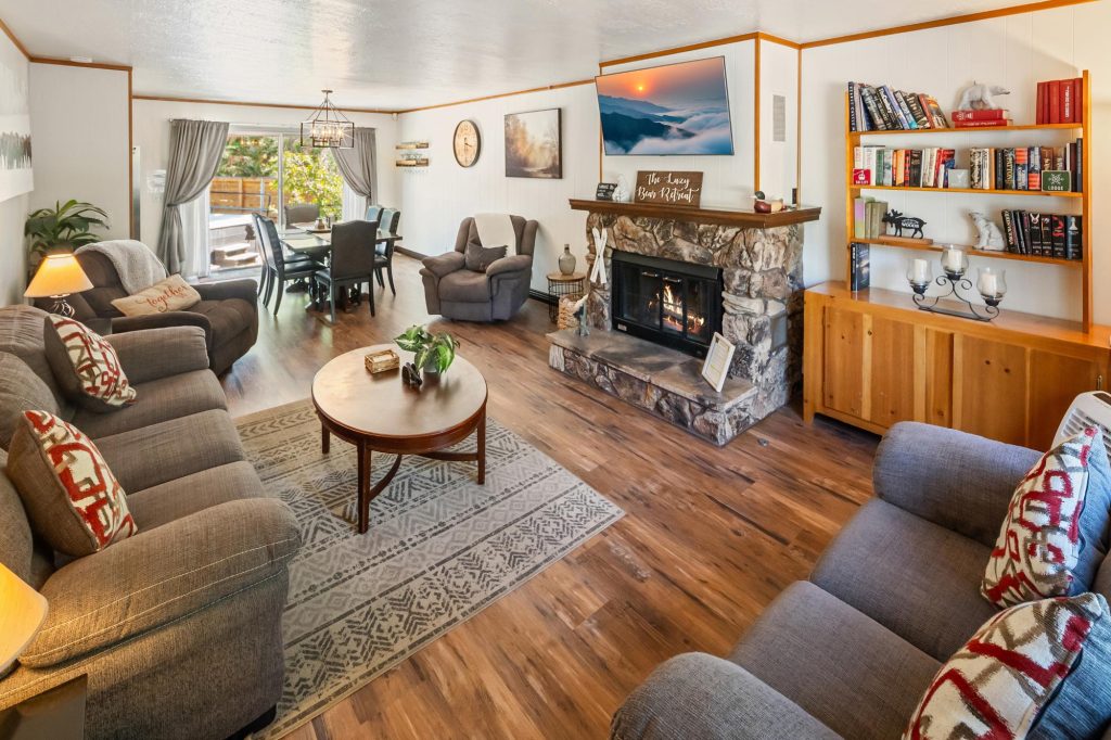 Cozy Lazy Bear Retreat living room with stone fireplace, comfortable seating, wooden floors, and warm cabin decor
