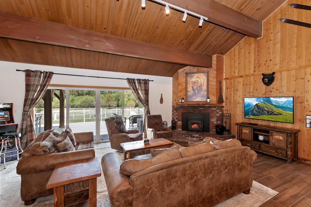 Cozy Meadow's Edge cabin living room with wood walls, fireplace, comfortable seating, and rustic mountain decor