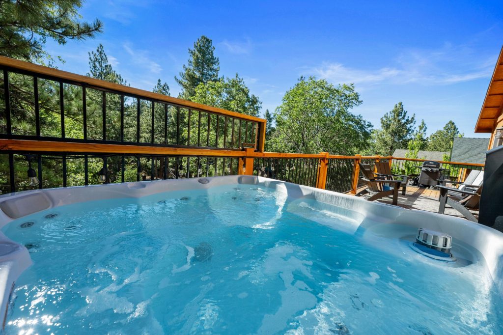 Outdoor hot tub at Chalet Cervo surrounded by trees with a spacious deck and mountain cabin setting