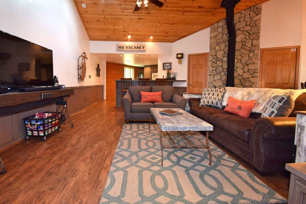 Cozy Falling Leaf Retreat living room with stone fireplace, comfortable sofas, TV area, and warm wood accents