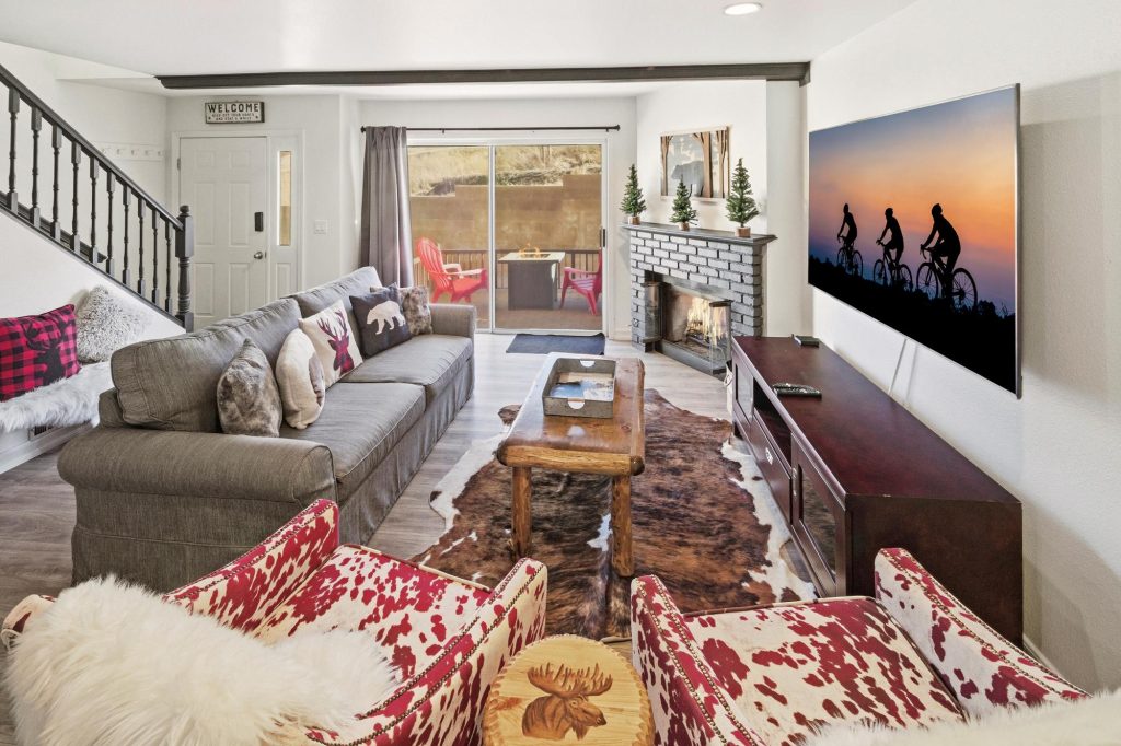 Dorneys Den living room with a cozy fireplace, sectional sofa, rustic coffee table, and large TV