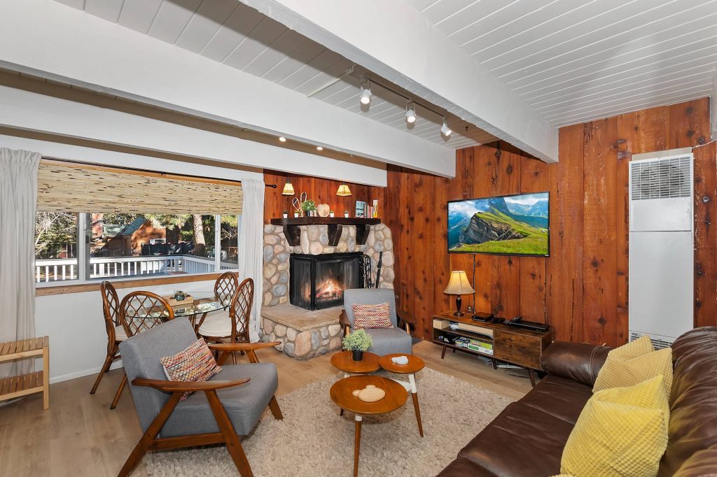 Peregrine Pines living room with stone fireplace, wood walls, seating, and TV