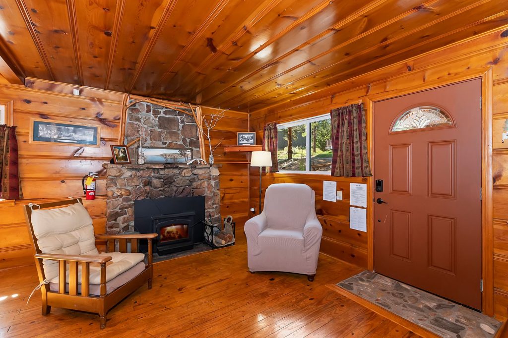 Fairytale Place cabin interior with wood walls, stone fireplace, cozy chairs, and rustic design