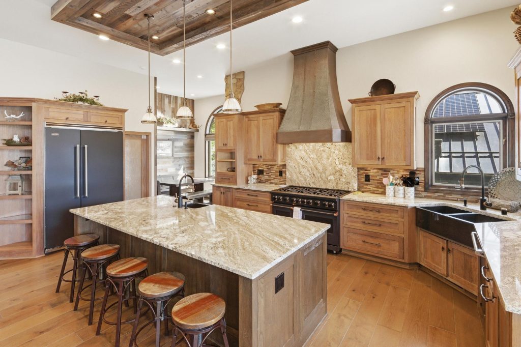 Spacious kitchen interior at Gilner Point Lakefront featuring a large island, wood cabinetry, granite countertops, and modern appliances