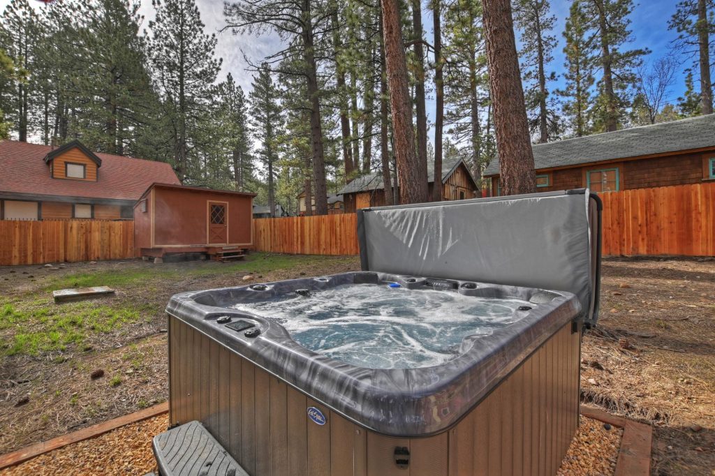 Outdoor hot tub at Knights Cabin in the Pines surrounded by tall pine trees and a peaceful forest setting