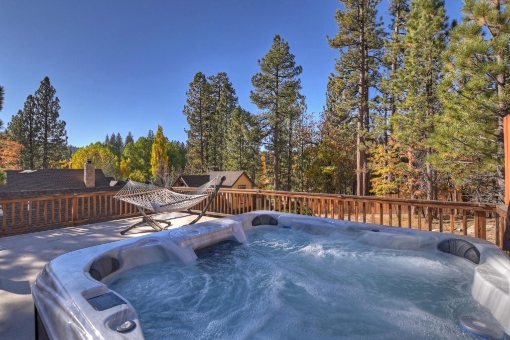 Outdoor hot tub on the deck at Big Bear Escape cabin surrounded by pine trees and mountain scenery in Big Bear Lake