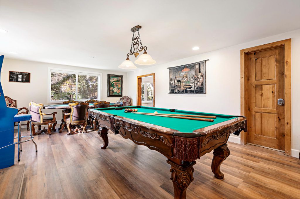 Game room with wood pool table and vintage chairs at The Great Gatsbear Cabin.