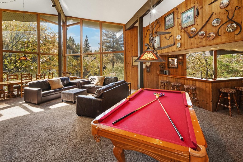 Mountain cabin game room featuring a pool table, leather seating, bar area, and floor-to-ceiling windows