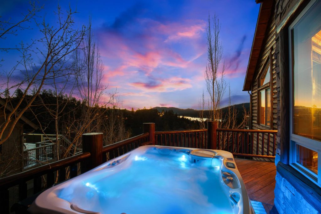 Grandview Lodge outdoor hot tub on a wooden deck overlooking mountain and lake views at sunset