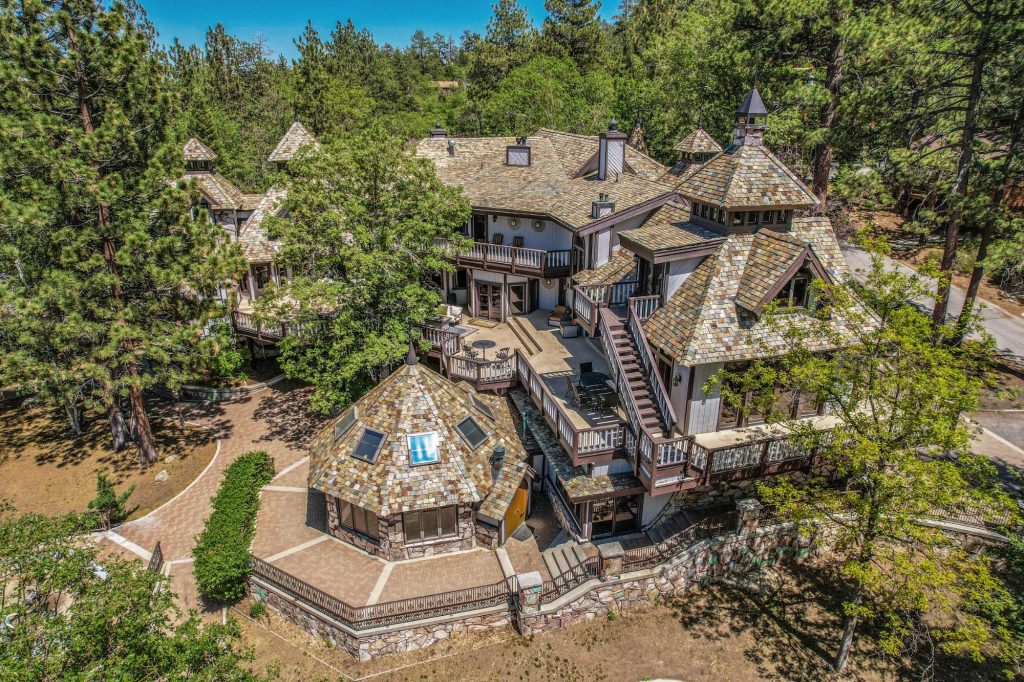 Aerial view of The Edgewood Mansion surrounded by tall pine trees in Big Bear Lake