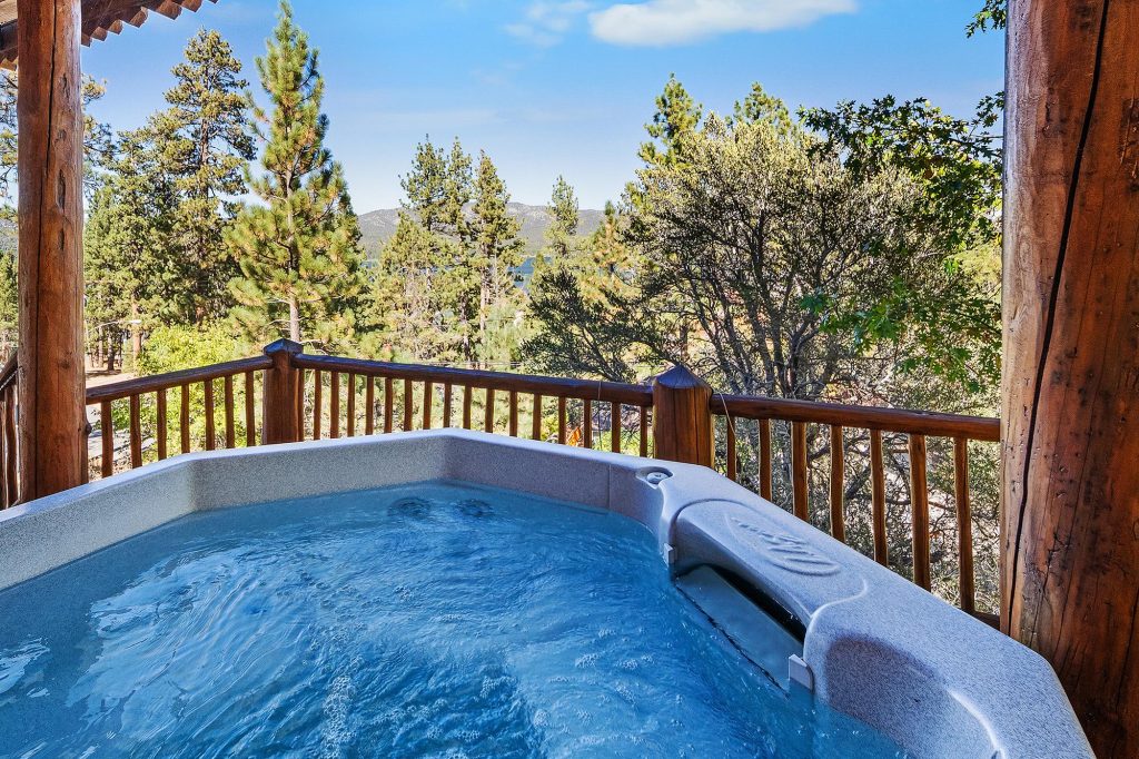 Outdoor hot tub on a wooden deck at Talmadge Lodge with forest views and mountain scenery in Big Bear Lake, CA