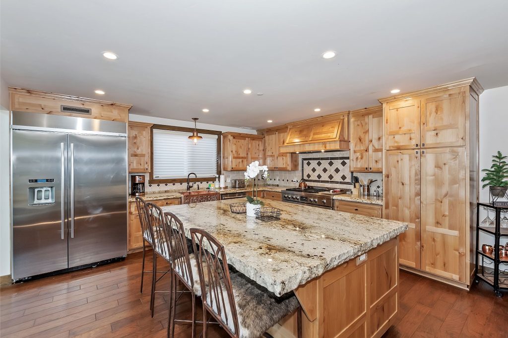 Spacious Moonlight Lodge kitchen with wooden cabinets, granite island, stainless steel appliances, and modern cabin design in Big Bear Lake, CA