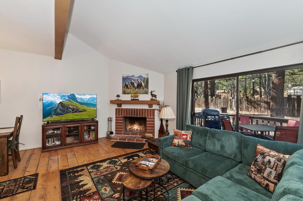 Cozy living room at Bearfoot by the Bay with fireplace, sectional sofa, mountain decor, and forest views