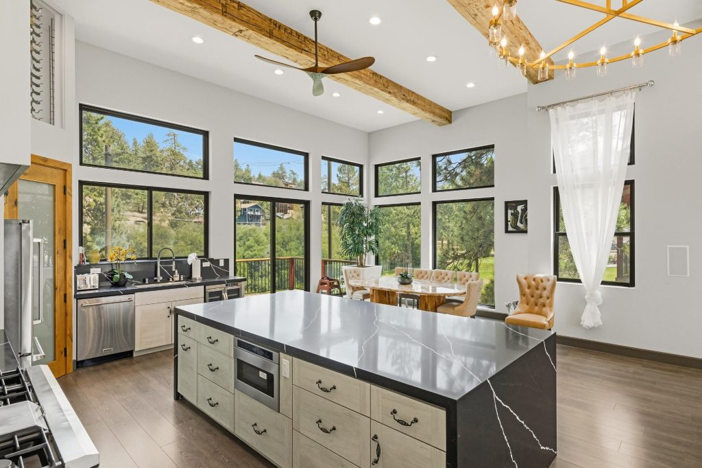 Bright modern kitchen interior with a large island, panoramic windows, dining area, and mountain views in Big Bear Lake