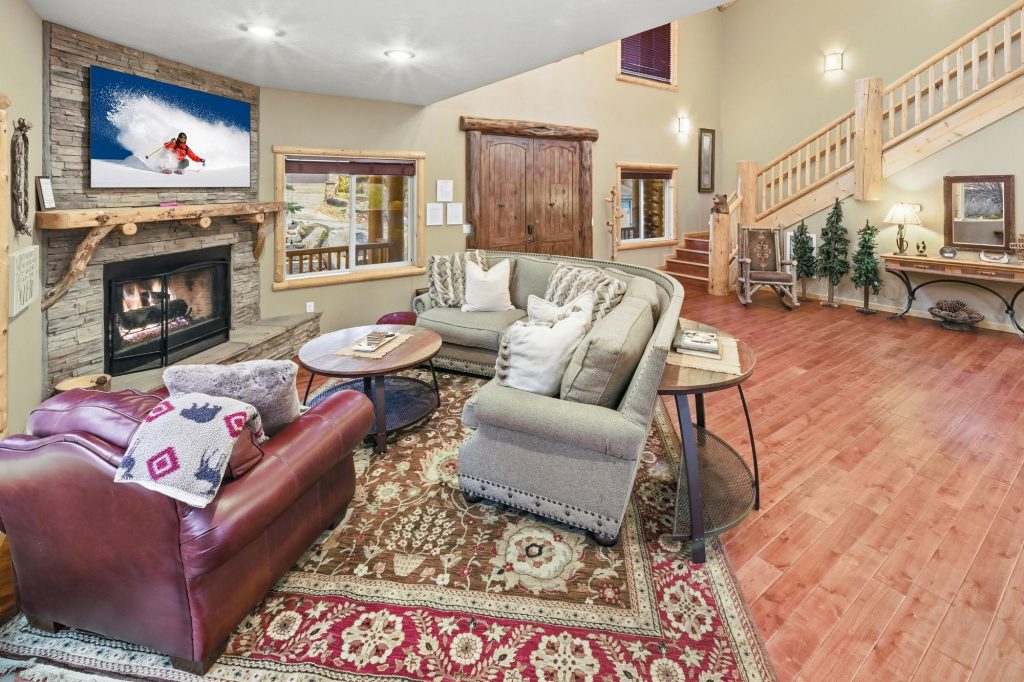 Wolf Den Estate living room with stone fireplace, cozy seating, rustic wood details, and mountain decor