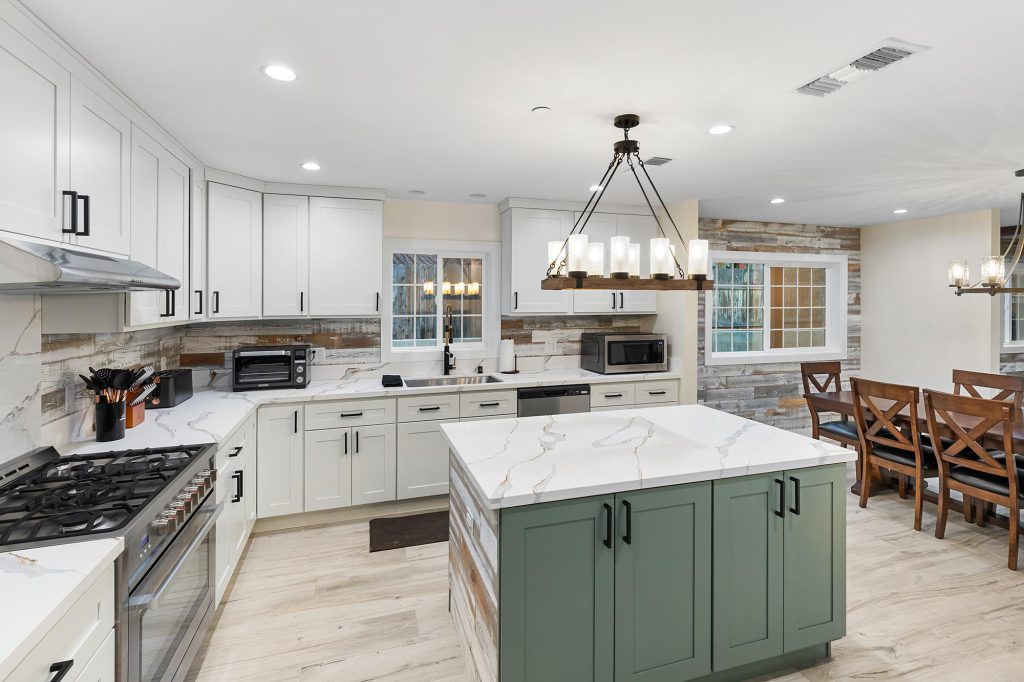 A modern kitchen in a Big Bear vacation home features white cabinets, a green island, and wood accent walls.