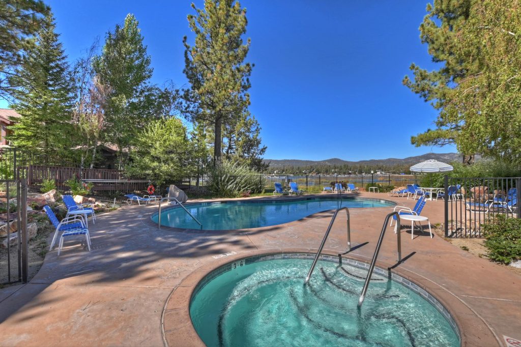 Outdoor pool and hot tub area at Amoroso Haven cabin with lake views, lounge chairs, and mountain scenery in Big Bear Lake