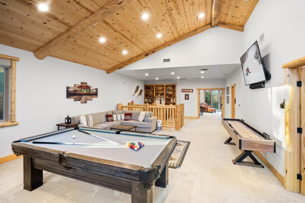 Luna Lodge game room with pool table, shuffleboard, sofa, and cabin-style decor.