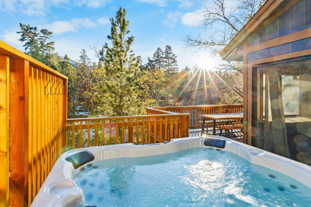 Outdoor hot tub on a sunny deck at Echo Inn in the Canyon, surrounded by pine trees.