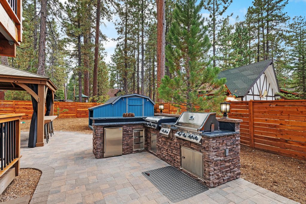 Outdoor backyard area featuring a built-in barbecue grill with a stone countertop and wooden pergola.