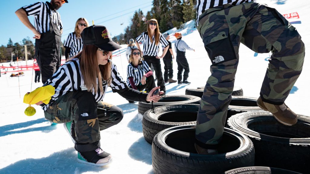 Referees oversee participants stepping through tire obstacles during the Bear Bowl snow football event in Big Bear Lake