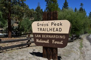 A sign for "Grays Peak Trailhead, San Bernardino National Forest" stands amidst trees, indicating a hiking spot at Big Bear.