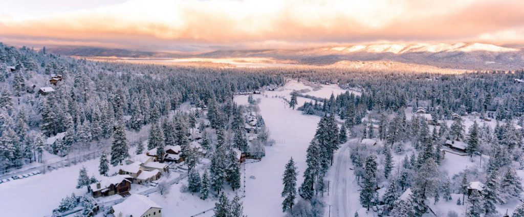 Aerial view of Big Bear Lake, showcasing a picturesque snowy mountain town surrounded by white-capped peaks.