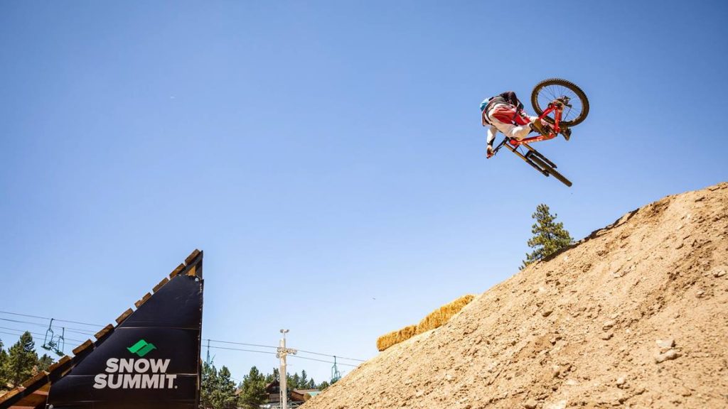 Athlete performing extreme sports in an outdoor mountain setting with spectators in the background