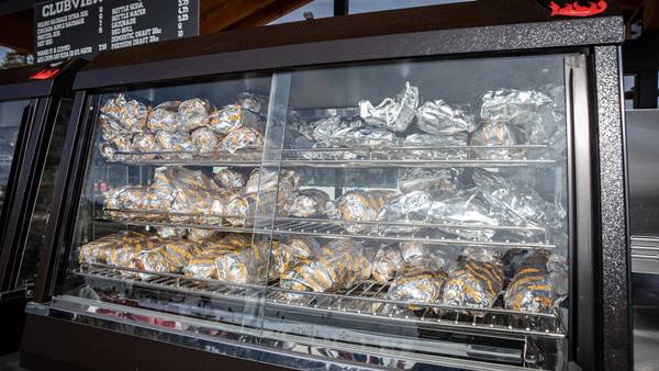 Wrapped cheesesteaks displayed inside a heated food case at Johnny’s Marina.