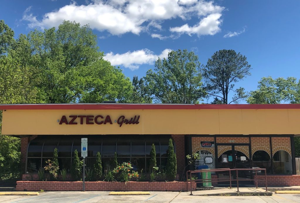 The exterior of Azteca Grill, a restaurant in Big Bear, on a sunny day with trees and a blue sky in the background.
