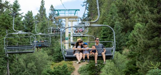 A family riding a ski lift in Big Bear, California, amidst beautiful forested mountains, enjoying a scenic winter experience.