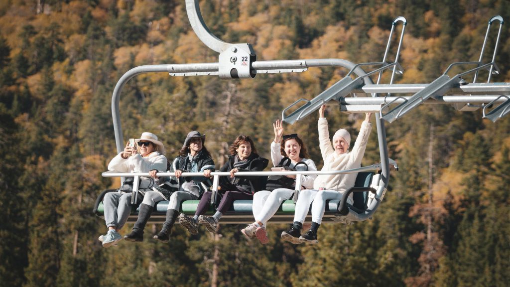 Passengers on a ski lift ascend the slopes at Sky Chair, Big Bear, surrounded by a winter landscape.