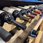 n image of multiple bottles of wine lying horizontally on a wooden wine rack at Big Bear