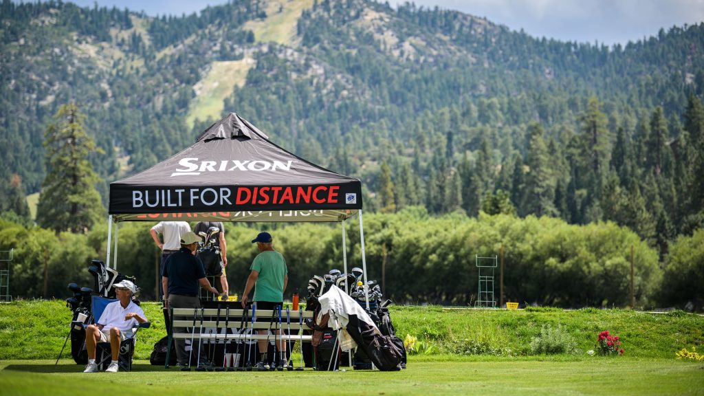 Golfers at a Srixon demo event under a branded tent on a sunny course
