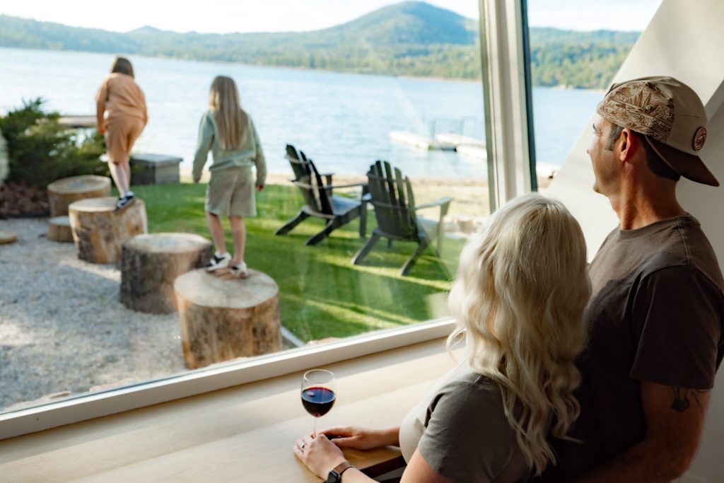 Family relaxing inside a lakefront cabin while overlooking Big Bear Lake and enjoying the scenic waterfront view.