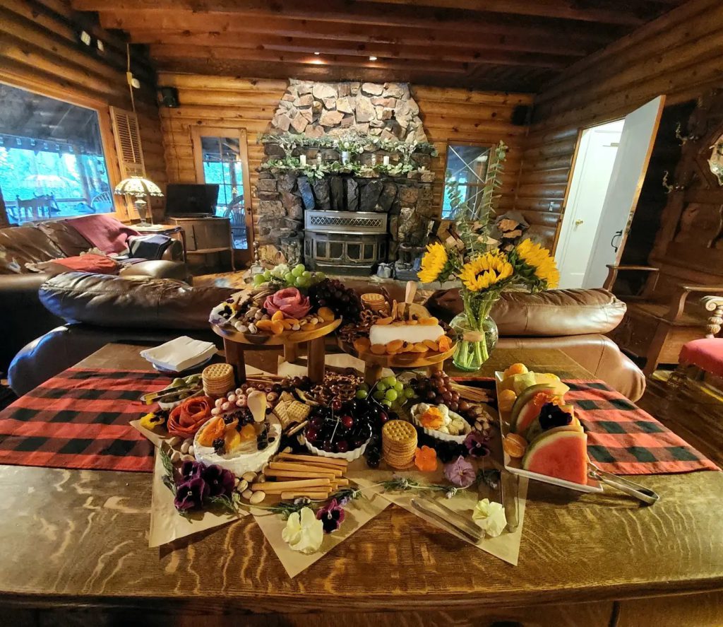 A beautifully arranged grazing table with various foods and drinks set in a rustic log cabin in Big Bear.