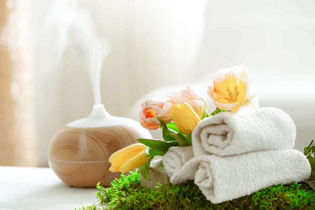 An aroma diffuser, towels, and flowers create a serene atmosphere at a Big Bear spa.